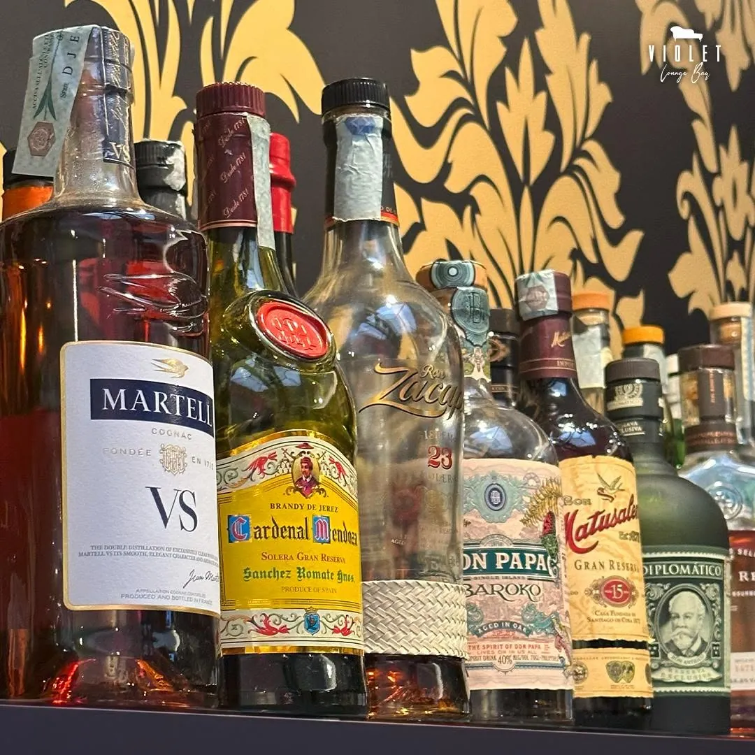 La parete damascata nera e oro con le bottiglie del Violet Lounge Bar