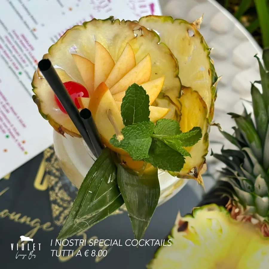 Cocktail servito dentro l'ananas con ventaglio di mela e menta
