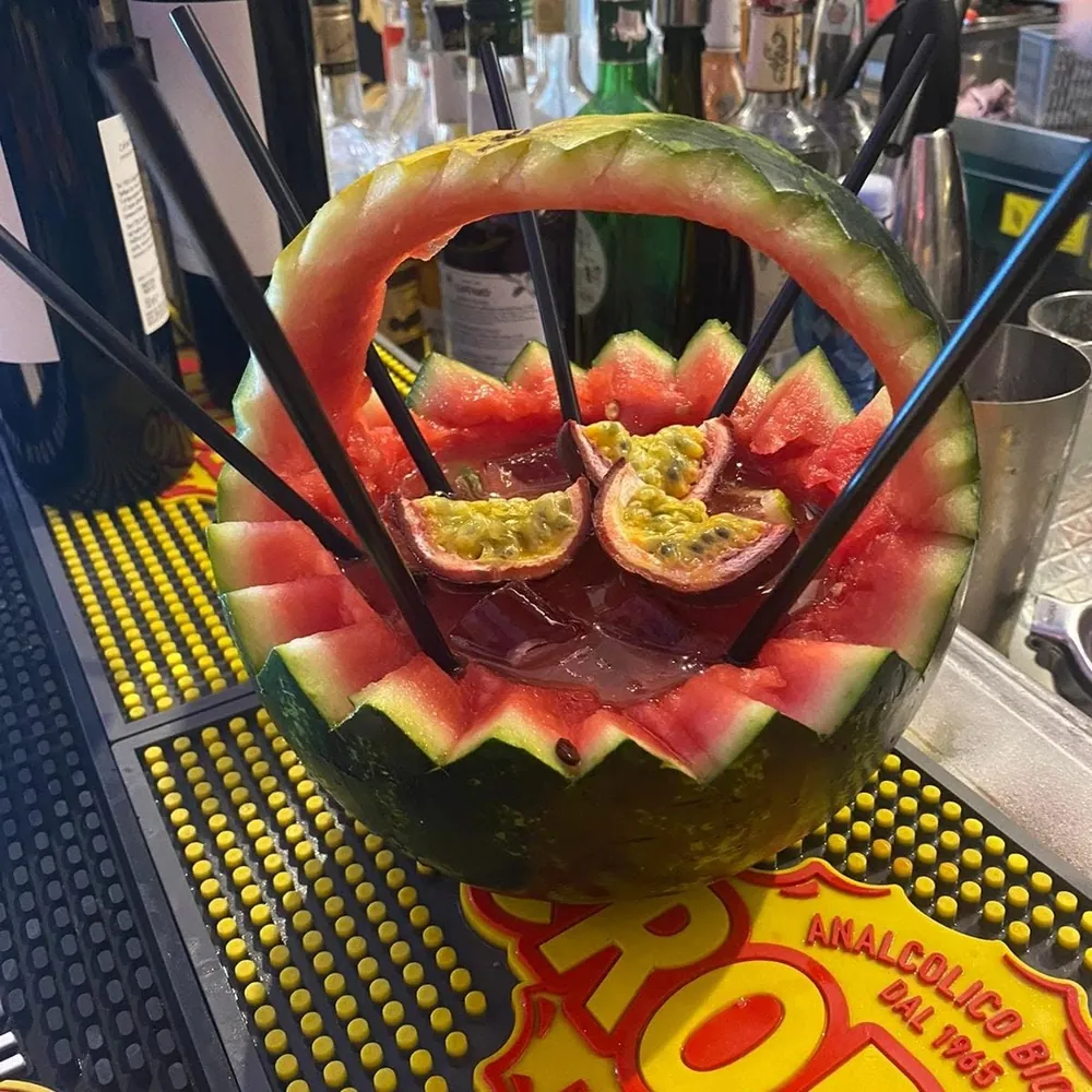 Cocktail servito dentro un'anguria intagliata con frutto della passione