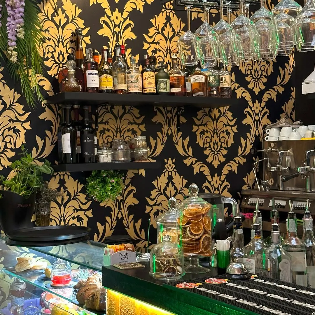 La sala del Violet Lounge Bar, con la carta da parati damascata nera e oro e il bancone